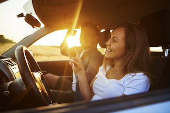 Young woman and man smiling and happy in car at sunset